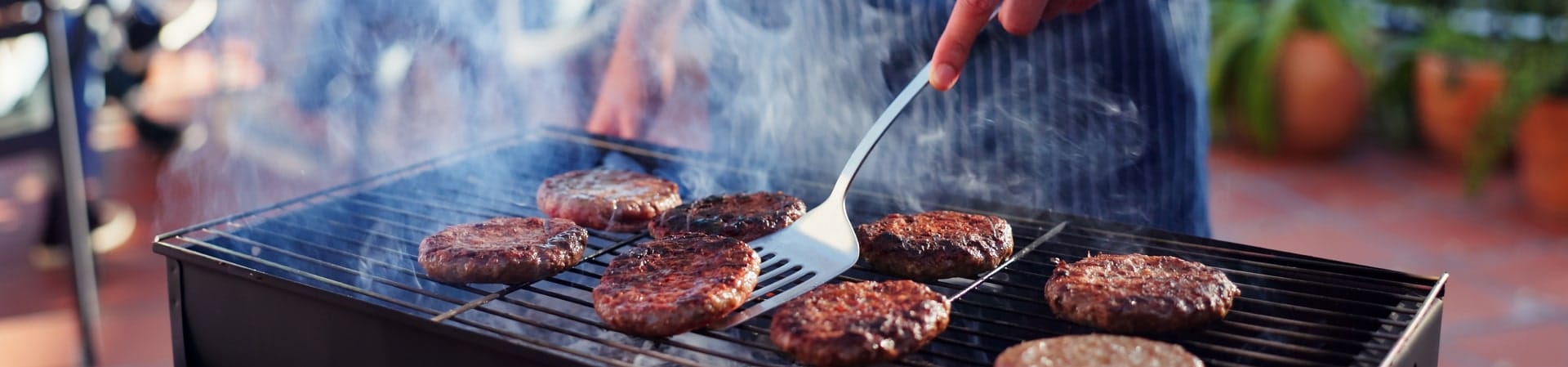 Burgers enhanced with IFF Taste's meat flavor solutions are being flipped on a grill