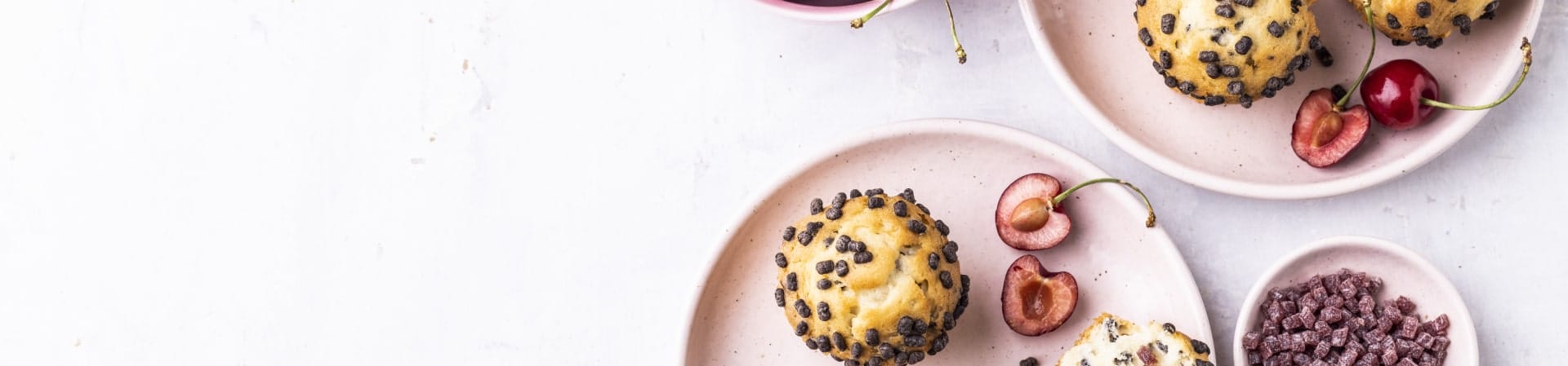 muffins formulated with IFF Taste sugar-reduction solutions, sitting on plates next to cherries