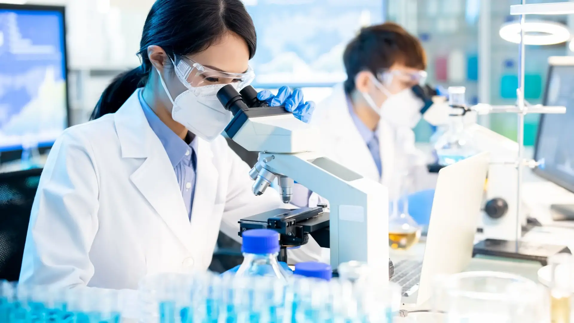 Technicians wearing PPE handling enzyme materials in a lab setting, illustrating safe industrial practices.
