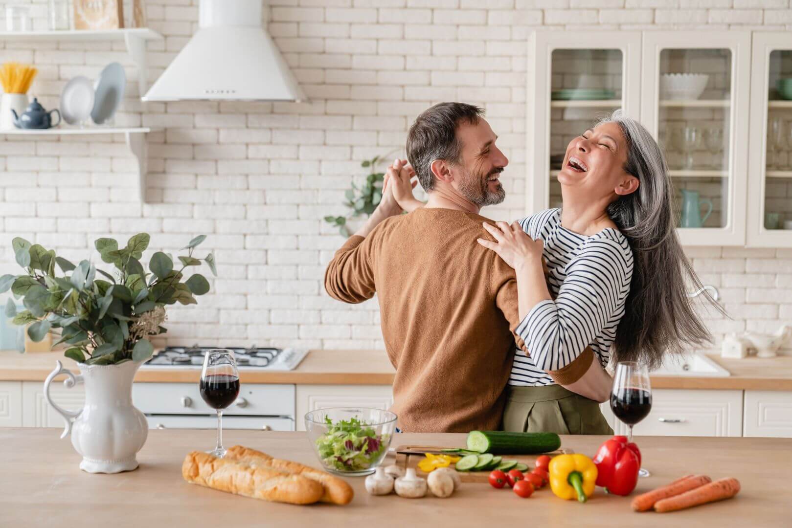 Couple smiling and dancing in the kitchen, midway through consuming Mood Intelligence-flavored products and cooking a meal