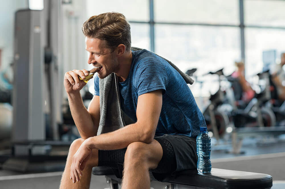 man in gym eating protein bar