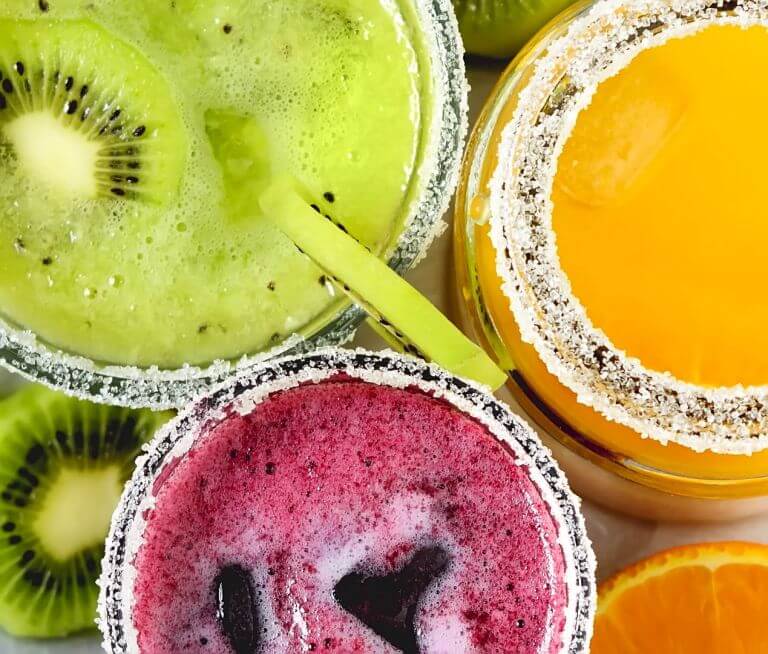 Photo taken from above of multi-colored, cold fruit drinks in glasses - kiwi, berry and orange-citrus.